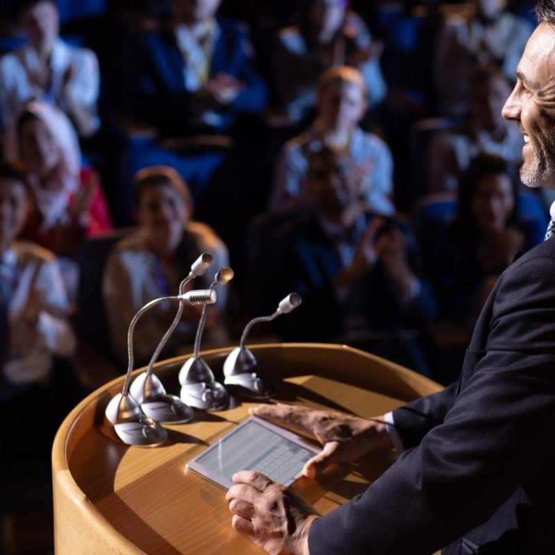 side-view-of-caucasian-businessman-standing-and-giving-presentation-in-the-auditorium.jpg
